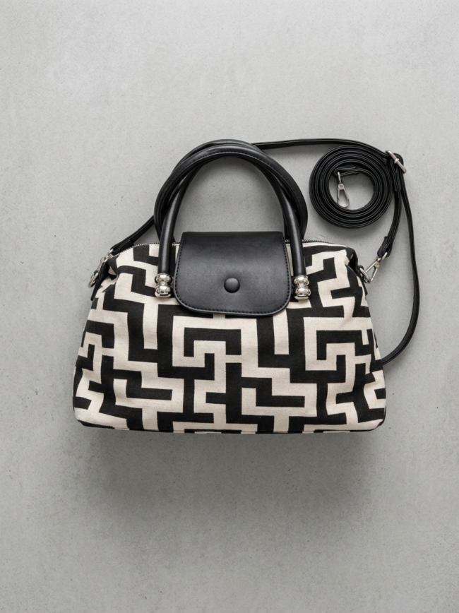 8DTqm_6TjRc2Y5B49qt4lo Black-and-white geometric patterned handbag with black leather handles on a gray surface