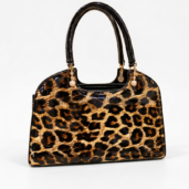 Leopard print handbag with shiny black handles and gold-tone hardware on a light background