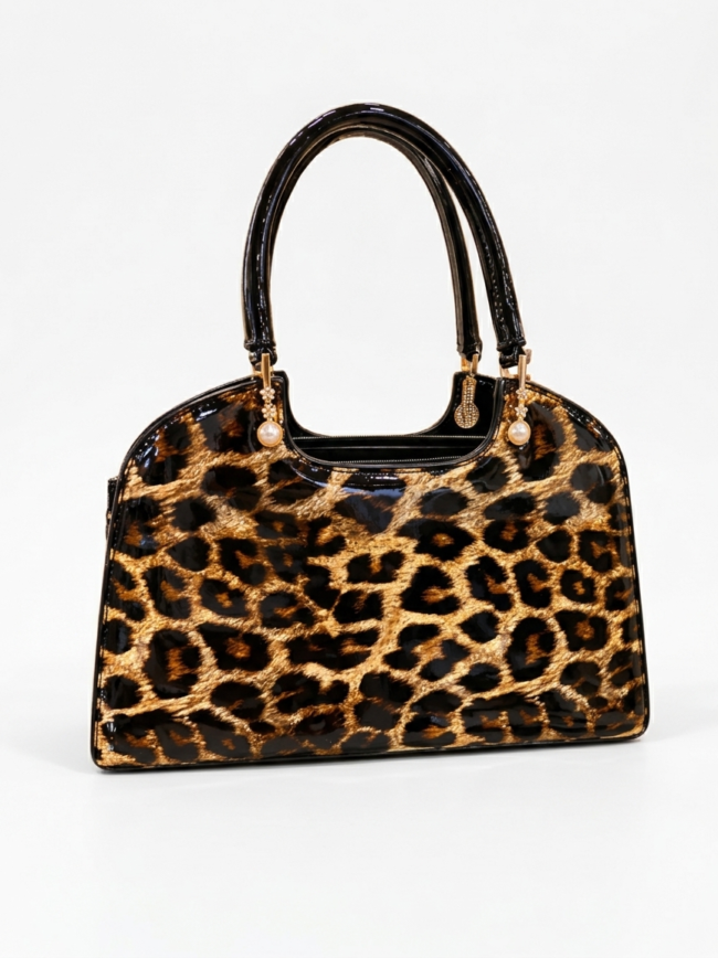 Leopard print handbag with shiny black handles and gold-tone hardware on a light background