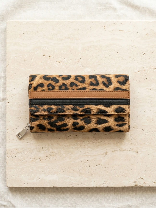 Leopard print wallet with a zipper, placed on a light stone surface.