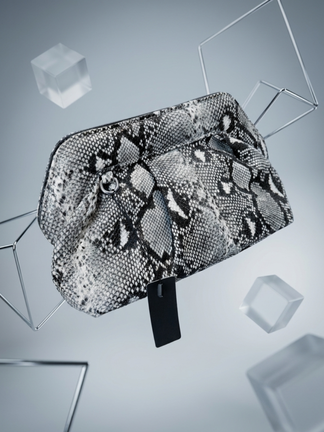 aD-sC_Xly8J7o9VbcMWOdI Snake-print handbag with a black tag, suspended among geometric metal frames and translucent cubes for a fashion product image.