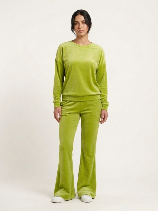 aVFwfogDhBWe8PszTw7kCJ Full-length view of a person wearing a lime green velour tracksuit (long-sleeve top and flared pants) with white sneakers, in a neutral studio backdrop.