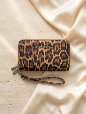 b-5kNSK_IAjfNj8tYCI4Xy - Merlin Luxury Leopard print zip wallet with a matching wrist strap resting on a light beige fabric and stone surface.