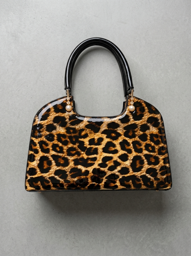 Leopard print handbag with black glossy handles and pearl-adorned gold hardware on a gray background