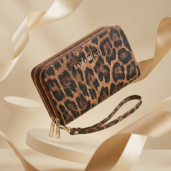 Leopard-print wallet with gold zippers and a matching wrist strap, displayed against a cream backdrop, branded Baci & Abbracci.
