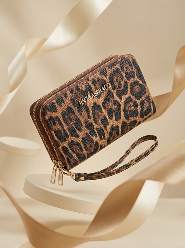 Leopard-print wallet with gold zippers and a matching wrist strap, displayed against a cream backdrop, branded Baci & Abbracci.