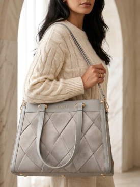 Woman in a cream knit sweater carries a light gray quilted handbag with gold hardware (MAXFLY).