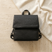 Black leather backpack with a textured surface on a light tiled floor.