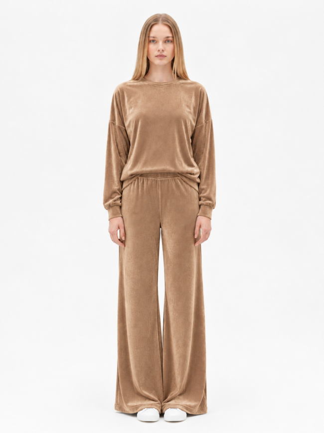Γυναικείο Σετ Φόρμας Κάμελ 4 Full-body shot of a model wearing a taupe velour loungewear set with an oversized long-sleeve top and wide-leg pants, paired with white sneakers, facing the camera.