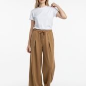 Woman wearing a white T-shirt and camel wide-leg pants with a drawstring, standing against a white background.