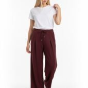 Model wearing a white t-shirt with burgundy wide-leg drawstring pants and white sneakers against a white backdrop.