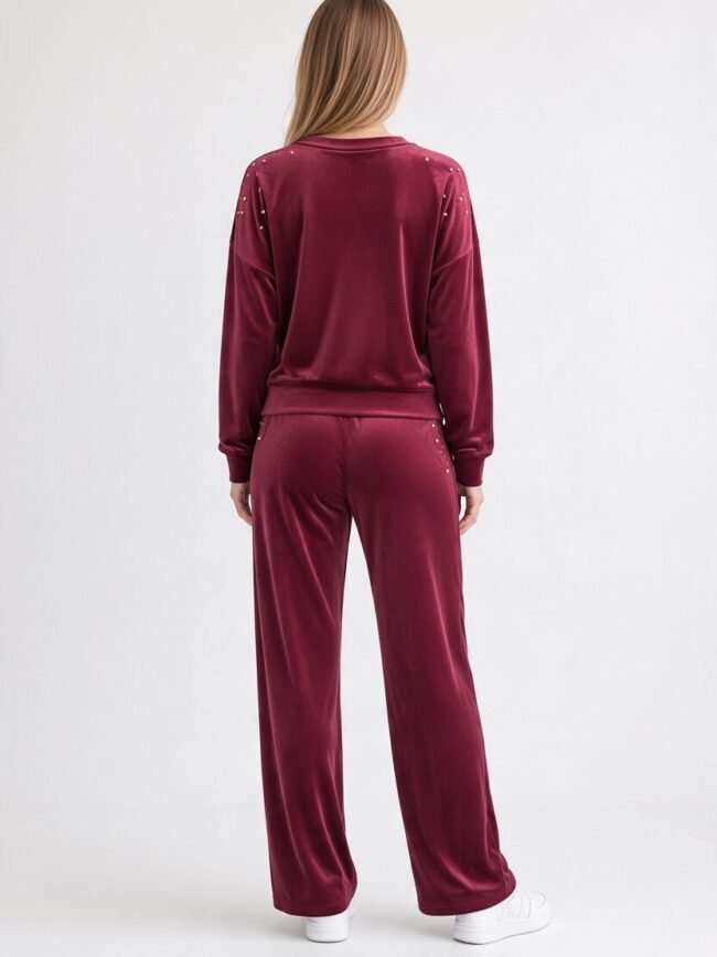 Velvet Μπορντό 3 Back view of a woman wearing a burgundy velour tracksuit with small studs on the shoulders and sides.