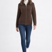 Full-body shot of a woman modeling a brown zip cardigan with a fur collar, white turtleneck, blue jeans, and white sneakers, walking toward the camera.