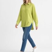 Model wearing a lime green oversized button-down shirt, blue jeans, and white sneakers.