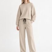 Model wearing a beige loungewear set: an oversized sweatshirt with ribbed sleeve details and matching drawstring pants, white sneakers.