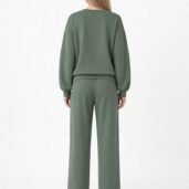 Back view of a person wearing an olive-green oversized sweatshirt and wide-leg pants set, white sneakers visible at the bottom.
