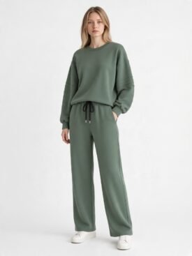 Model wearing a sage green as-looks-like lounge set: oversized sweatshirt with ribbed sleeves and matching wide-leg drawstring pants, white sneakers