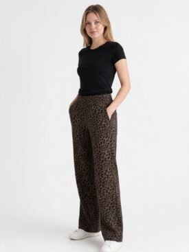 Woman standing in a black short-sleeve top and brown leopard-print wide-leg pants with hands in pockets, white sneakers