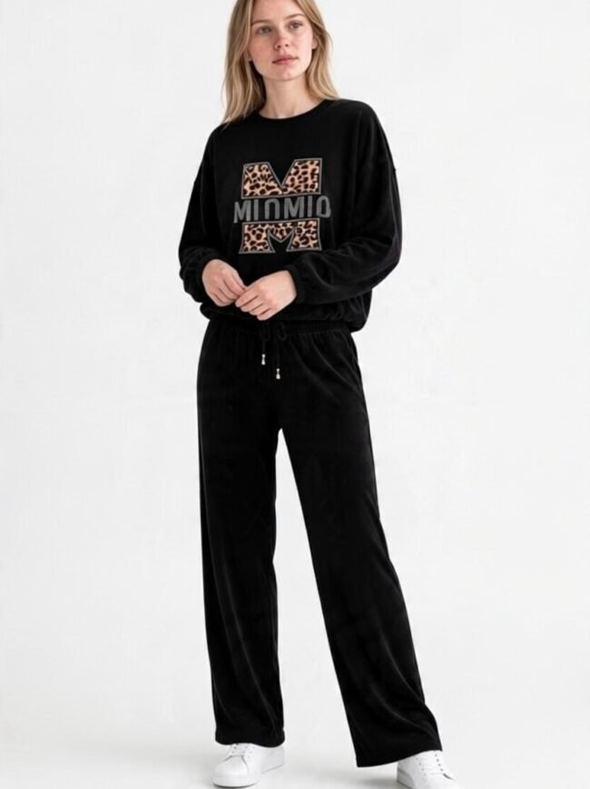 Μαύρο Σετ 4 2 Model wearing a black velour tracksuit with a leopard‑print 'M' logo sweatshirt and matching wide‑leg pants, white sneakers, against a white backdrop.
