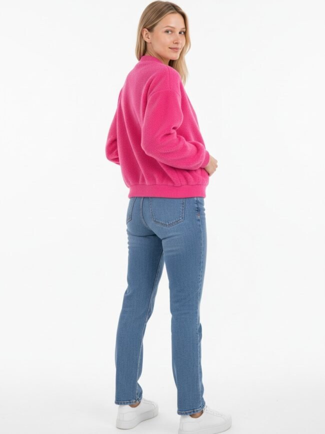 Μοντέλα μόδας AI-27f67d16-9f04-4e23-a0a3-cfea95784b02 Woman standing in a pink sweater and blue jeans, turned slightly to the side, facing camera with a subtle smile, white sneakers