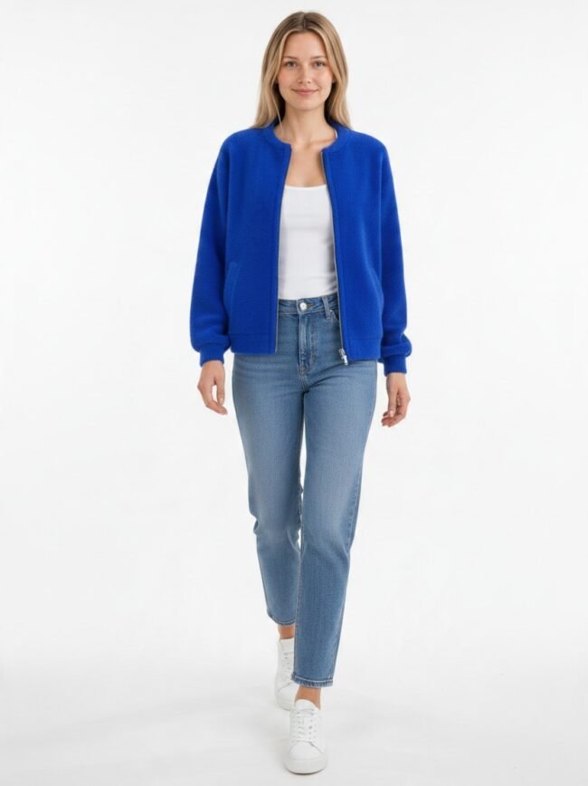 Μοντέλα μόδας AI-2ddee310-ec6b-44f0-9a39-059b63573b8d Full-body portrait of a woman in a royal blue bomber jacket, white top, light-wash jeans, and white sneakers against a white studio background, walking toward the camera.