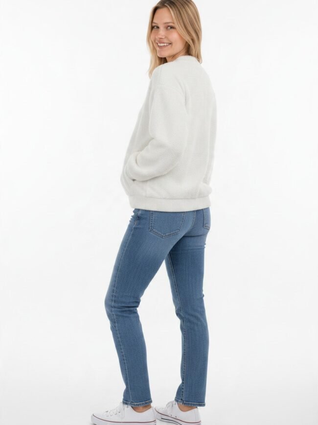 Μοντέλα μόδας AI-bcdcdc67-16d8-4884-8d6f-93a079b4bdaa Smiling woman in a white textured sweater, blue jeans, and white sneakers, turned slightly to the side.