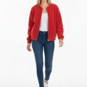 Woman standing in a bright red textured cardigan over a white top, with blue jeans and white sneakers, facing the camera.