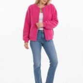 Woman wearing a bright pink zip-up cardigan over a white top, blue jeans, and white sneakers, posing against a white background.