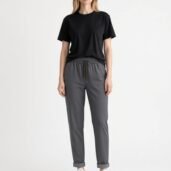 Full-body: woman in black T-shirt, gray joggers, white sneakers, facing the camera.