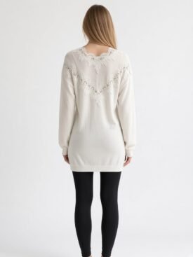 Back view of a woman in a white knit sweater with lace yoke detail and black leggings.