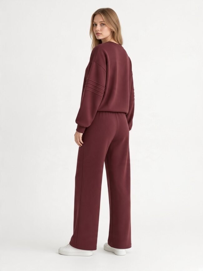 Woman in a burgundy loungewear set facing away, showcasing a matching long-sleeve top and wide-leg pants with white sneakers.
