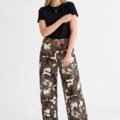 Model in black T-shirt with loose camouflage pants, brown belt, and white sneakers