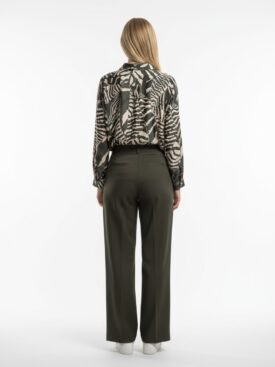 Back view of a person wearing a black-and-beige animal print blouse tucked into olive-green wide-leg pants, white sneakers, standing against a white background