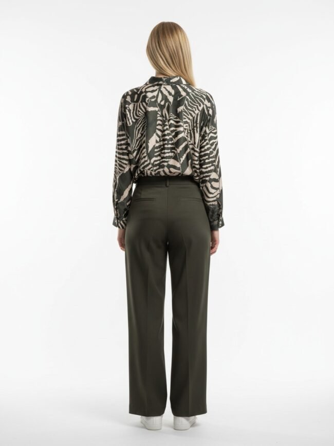 Back view of a person wearing a black-and-beige animal print blouse tucked into olive-green wide-leg pants, white sneakers, standing against a white background