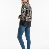 Woman wearing a loose black-and-beige zebra-print blouse, blue jeans and white sneakers, standing in profile.