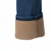 Close-up of a blue denim pant leg with a brown textured boot cuff at the ankle.